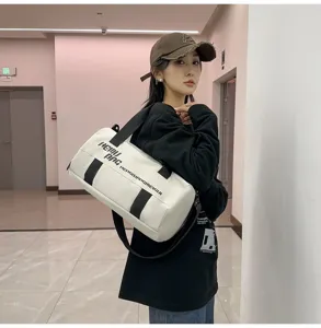 Detailed view of white cylindrical travel duffel bag with black straps and large capacity.