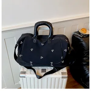 Black travel duffel bag with white bow pattern, spacious storage for gym and weekend trips.