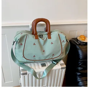 Large capacity canvas travel duffel bag with bow embroidery and leather handle for trips.