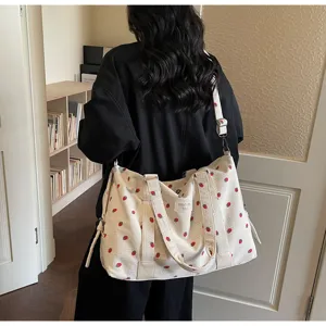 Close-up of large canvas travel bag with cute red strawberry print and sturdy handles.