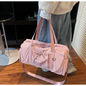 Detail view of large capacity pink travel shoulder bag with cute bow and durable strap.