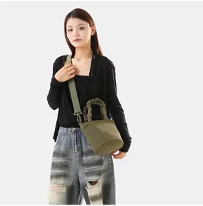 Vue détaillée du sac seau tendance en toile unie porté, montrant la texture et la sangle.