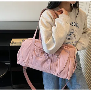 Pink travel duffel bag detail showcasing large capacity, waterproof fabric, and shoulder strap.
