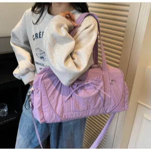 Detailed shot of a large capacity purple shoulder duffel bag with cute bow and durable strap.