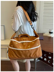 Detail view of brown travel duffel bag with cute lace trim and embroidered bows for women.