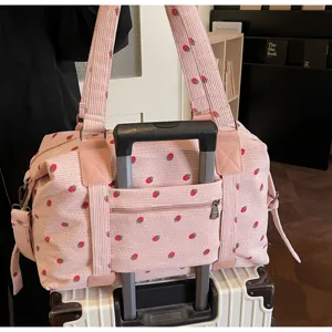 Pink corduroy travel duffel bag with cute strawberry print, luggage sleeve and shoulder strap.