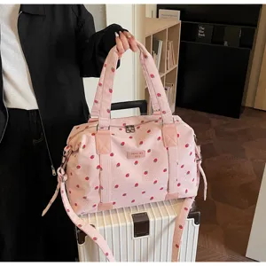 Pink corduroy strawberry travel duffel bag with shoulder strap and luggage trolley sleeve.