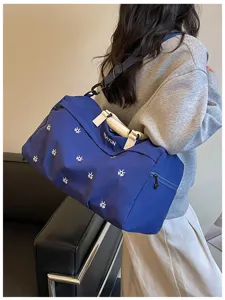 Detailed scene showing the large blue travel duffel bag worn by model with white patterns.