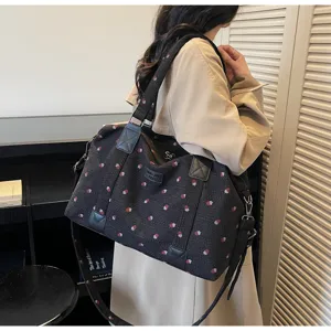 Detailed view of large black travel duffel bag with cute strawberry pattern and sturdy handles.