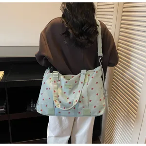 Detailed view of the large capacity strawberry print corduroy travel shoulder bag in use.