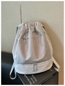 Détail de sac à dos cordon gris, matière imperméable avec compartiment inférieur zippé.
