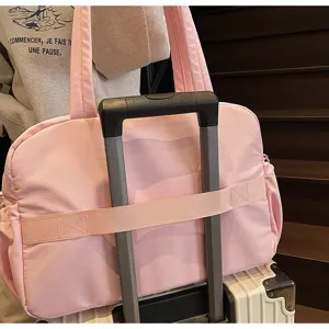 Nahaufnahme des rosa Reisetasche mit praktischem Koffergriff-Gurt für einfaches Reisen.