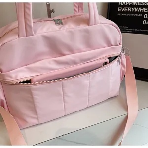 Nahaufnahme der rosa Reisetasche mit Frontreißverschlusstasche und Gerät auf weißer Theke.