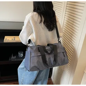 Detail de sac de voyage a carreaux gris, grand sac de sport pratique avec bandouliere.