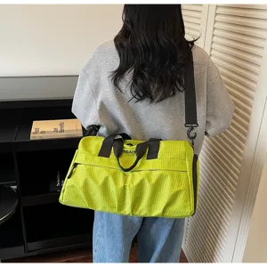 Vue détaillée du sac de voyage à carreaux verts, montrant le tissu durable et les poignées.