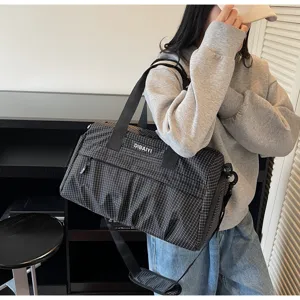 Vue détaillée du sac de voyage quadrillé noir avec poignées robustes et sangle réglable.