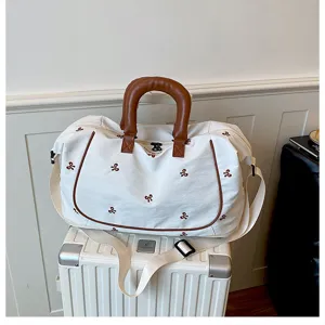 Large capacity canvas travel duffel bag with bow embroidery and brown leather handles.