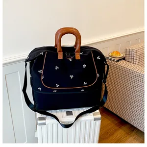 Large capacity black travel duffel bag with bow patterns, portable handle and shoulder strap.