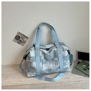 Detail view of the grey printed travel duffel bag showing reinforced blue straps and zippers.