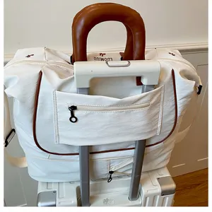 White travel duffel bag with brown handle and trolley sleeve for luggage, large capacity.