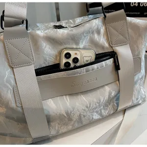 Detailed view of the silver travel duffel bag with front zipper pocket and durable straps.