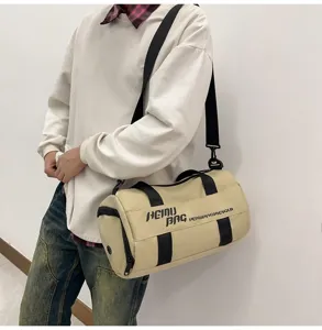 Beige cylindrical sports duffel bag detail showing shoulder strap and printed logo design.