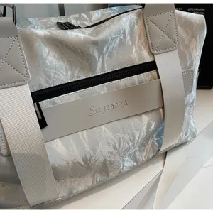 Silver crinkle texture travel duffel bag detail, showing durable straps and zipper pocket.