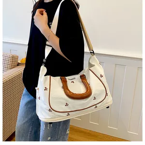 Large capacity canvas travel bag with brown handles and shoulder strap for gym and short trips.