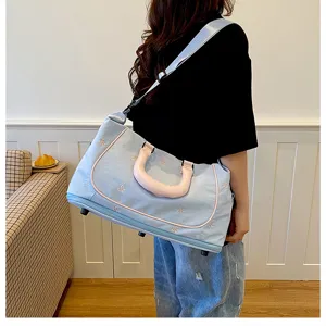 Detailed view of the light blue travel bag with cute bow embroidery and pink shoulder strap.