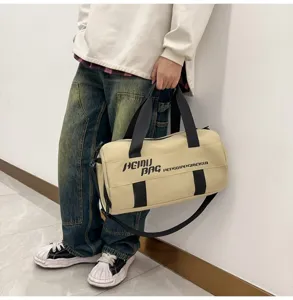 Close-up view of the beige cylindrical fitness duffel bag with black straps and side print.