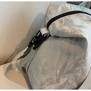 Close up detail view of silver crinkled travel bag featuring durable zipper and buckle.