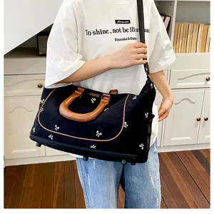 Black canvas travel duffel bag with brown handles and cute white bow patterns for women.