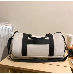 Detailed view of large capacity cylindrical gym duffel bag with black straps on wooden table.