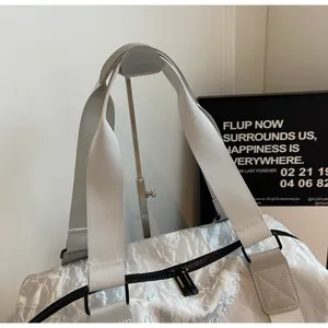 Close-up detail of silver crinkled PU travel bag handle and sturdy strap, modern style.