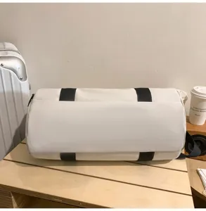 Detailed view of white cylindrical gym duffel bag with black straps, large capacity.