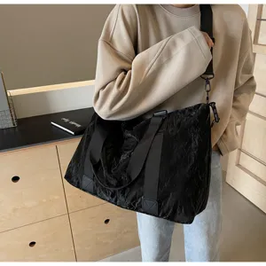 Detailansicht der schwarzen Reisetasche mit knittriger Textur und praktischen Trageriemen.