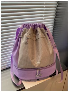 Gros plan sur le sac a dos violet et gris montrant la structure des poches et fermetures.
