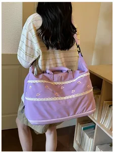 Detail of large capacity purple travel duffel bag featuring sweet lace trim and shoulder strap.