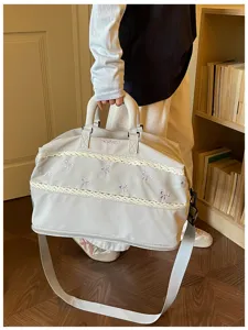 Detail shot of a large capacity summer travel duffel bag featuring cute bow embroidery and lace trim.