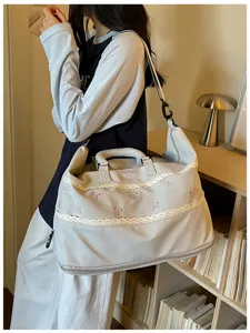 Detail shot of stylish bow embroidery travel duffel bag with lace trim, large capacity design.