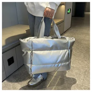 Silver metallic puffer tote bag detail, stylish quilted travel duffel and gym shoulder bag.