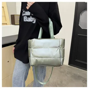 Puffer tote bag detail shot showing metallic silver green fabric, dual handles and side zipper.