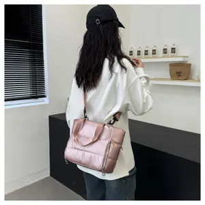 Pink glossy puffer shoulder bag detail view, lifestyle shot showing strap and zipper.