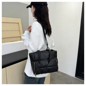 Detailed view of black quilted puffer shoulder bag, versatile sports and travel fitness bag.