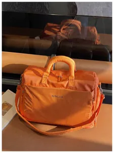 Orange travel duffel bag detail showcasing front zipper pocket and durable handle design.
