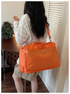 Detail view of orange travel duffel bag showing back wear scene and practical design.