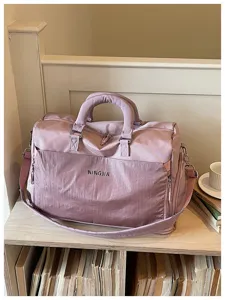 Detail view of the pink travel duffel bag with front mesh pocket and sturdy handles.