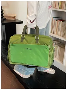 Large capacity green travel duffel bag detail view with front pocket and sturdy handles.