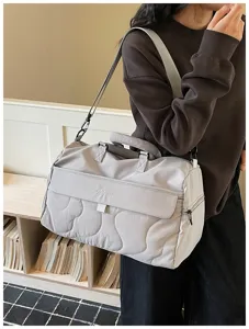 Detailed view of the large capacity quilted travel duffel bag in grey, showing texture and strap.