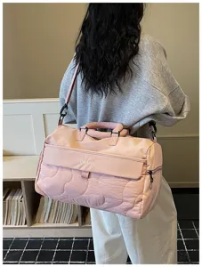 Pink quilted travel duffel bag detail view highlighting waterproof fabric and strap buckle.